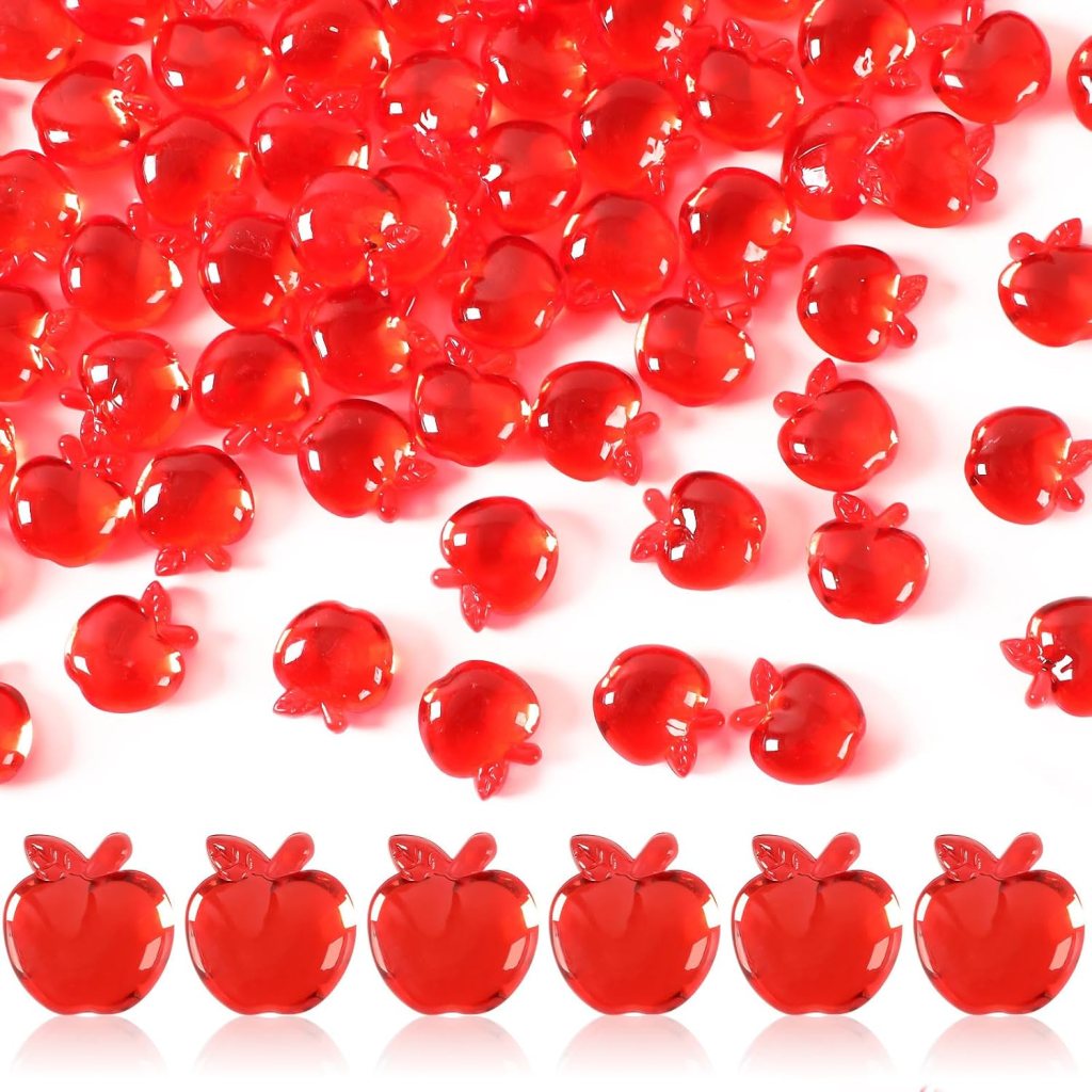 A variety of small, shiny red apple-shaped decorations scattered across a white background.