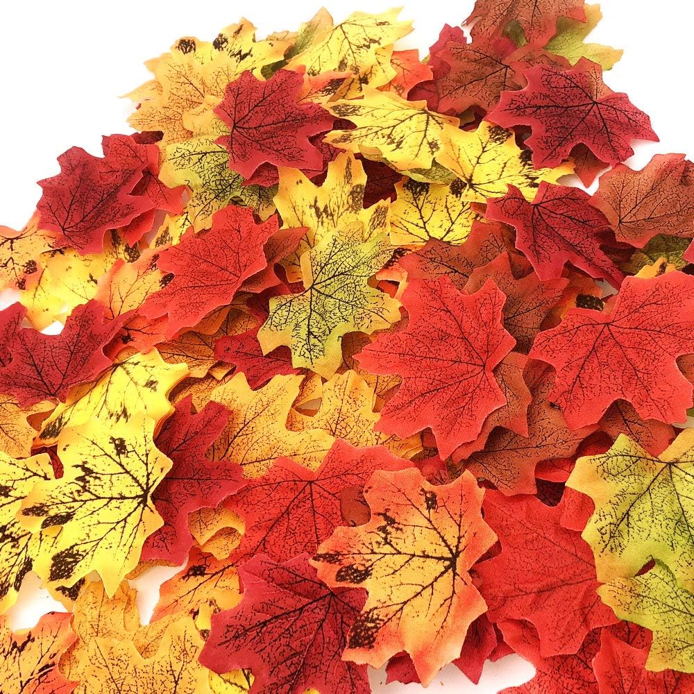 A close-up of colorful artificial maple leaves in various shades of red, orange, and yellow, scattered on a white background.