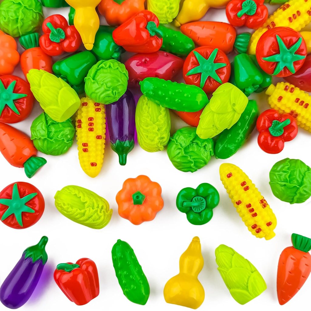 A colorful assortment of plastic vegetables including carrots, tomatoes, cucumbers, peppers, corn, and lettuce, arranged on a white background.