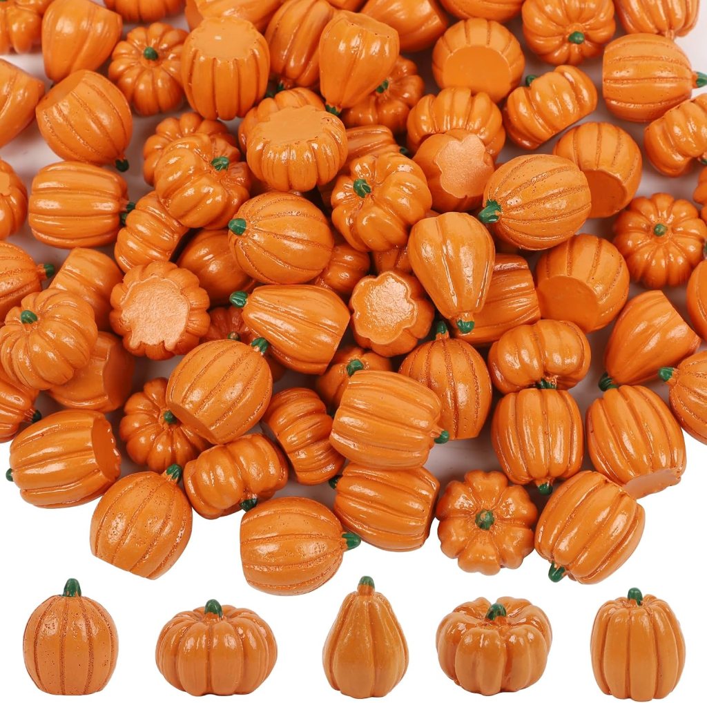 A collection of small orange plastic pumpkins in various sizes and shapes, including some with green stems, arranged haphazardly.