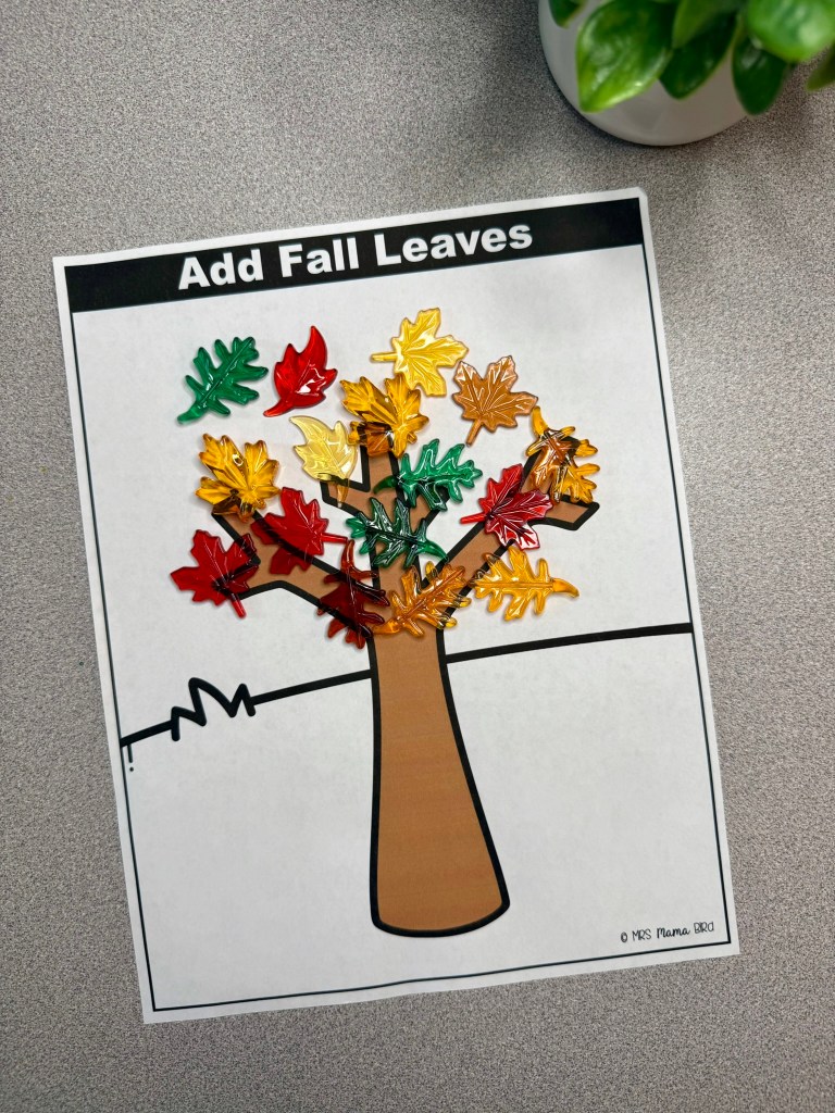 A craft activity sheet featuring a tree illustration with colorful plastic leaves in fall colors, labeled 'Add Fall Leaves' at the top.