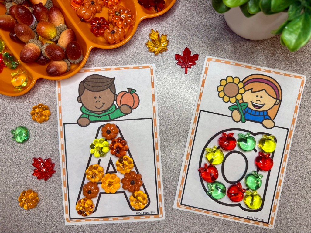 Colorful alphabet letter activities featuring the letters A and O made with decorative plastic pieces, alongside illustrations of a boy holding a pumpkin and a girl with a flower. Includes seasonal decorations like acorns and fall leaves.